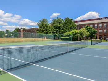 A tennis court with trees and a building in the background